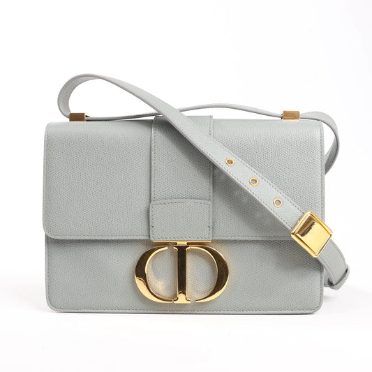 Dior Montaigne 30 gray leather shoulder bag featuring gold-tone CD logo clasp, flap closure, and adjustable leather shoulder strap with gold hardware.