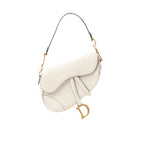 White Dior Saddle shoulder bag with curved flap, adjustable strap, and large gold-tone D charm hanging at the side