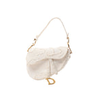 White Christian Dior Saddle canvas shoulder bag with frayed-edge detailing, tonal Christian Dior lettering, white strap and gold-tone D charm.