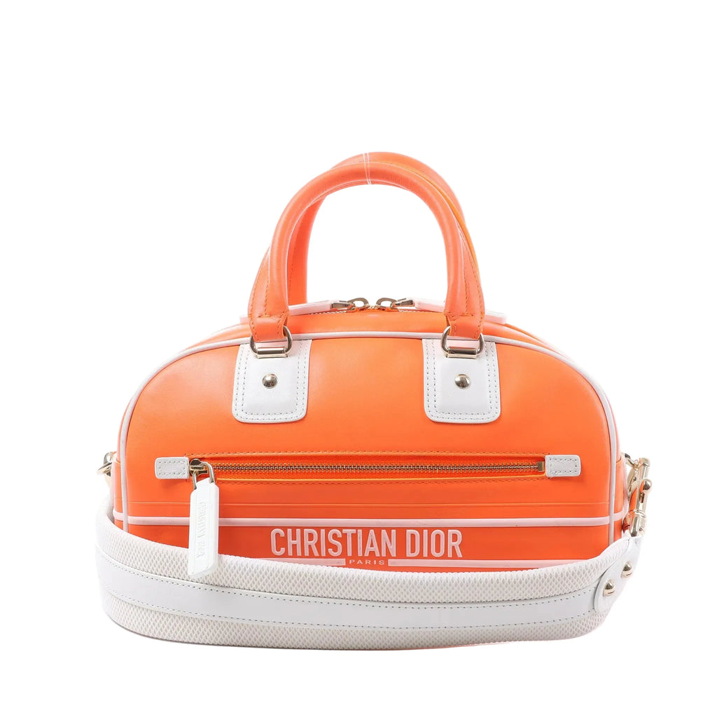 Dior Vibe Small orange bowling bag with white leather trim, rolled top handles, front zip pocket and wide detachable shoulder strap.