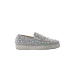 White Christian Louboutin slip-on sneaker covered in clear Swarovski crystals with white spike studs and white rubber sole, side view on white background
