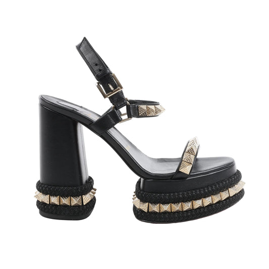 Christian Louboutin SUPERCLOU 130 black leather platform sandals with gold-tone pyramid stud accents, thick braided detailing around the sole, double ankle straps, and a high block heel, displayed in side profile on a white background.