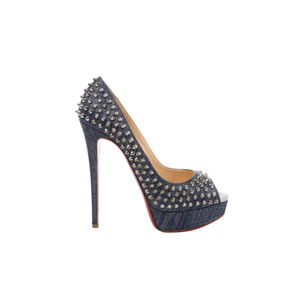 Side view of a Christian Louboutin navy denim pump with silver-tone spike studs, an open toe, raised platform, slim stiletto heel and visible red sole.