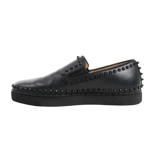 Christian Louboutin black leather slip-on sneakers in size 42 EU, featuring tonal black spike studs around the upper, heel, and sole edge, with elastic side panels and a black rubber sole, shown against a white background.