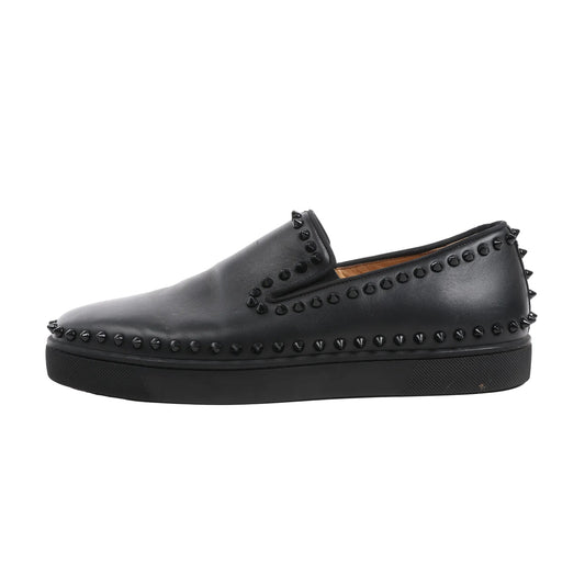 Christian Louboutin men's black leather slip-on sneaker in size 42 EU, detailed with black spike studs along the collar, toe, and heel, set on a black rubber sole.