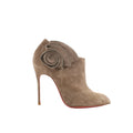 Christian Louboutin taupe suede Mrs Baba 100 bootie with spiral ruffle ankle detail, pointed toe, stiletto heel, and red sole on white background