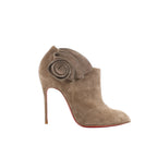 Christian Louboutin taupe suede Mrs Baba 100 bootie with spiral ruffle ankle detail, pointed toe, stiletto heel, and red sole on white background