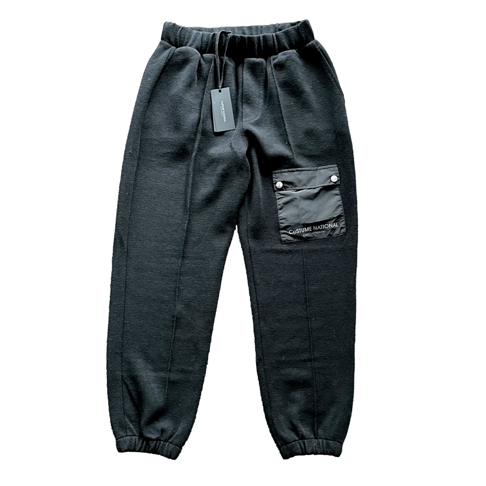 CoSTUME NATIONAL black jogger trousers with an elastic drawstring waistband, side pockets, utility cargo pocket with logo detail and elastic cuffs, laid flat on a white background.