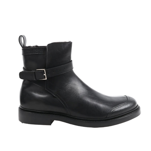 Dior Homme 15HSU short black leather ankle boot with a buckle strap, textured toe cap, rear pull tab, and low stacked heel, displayed in a side profile on a white background.