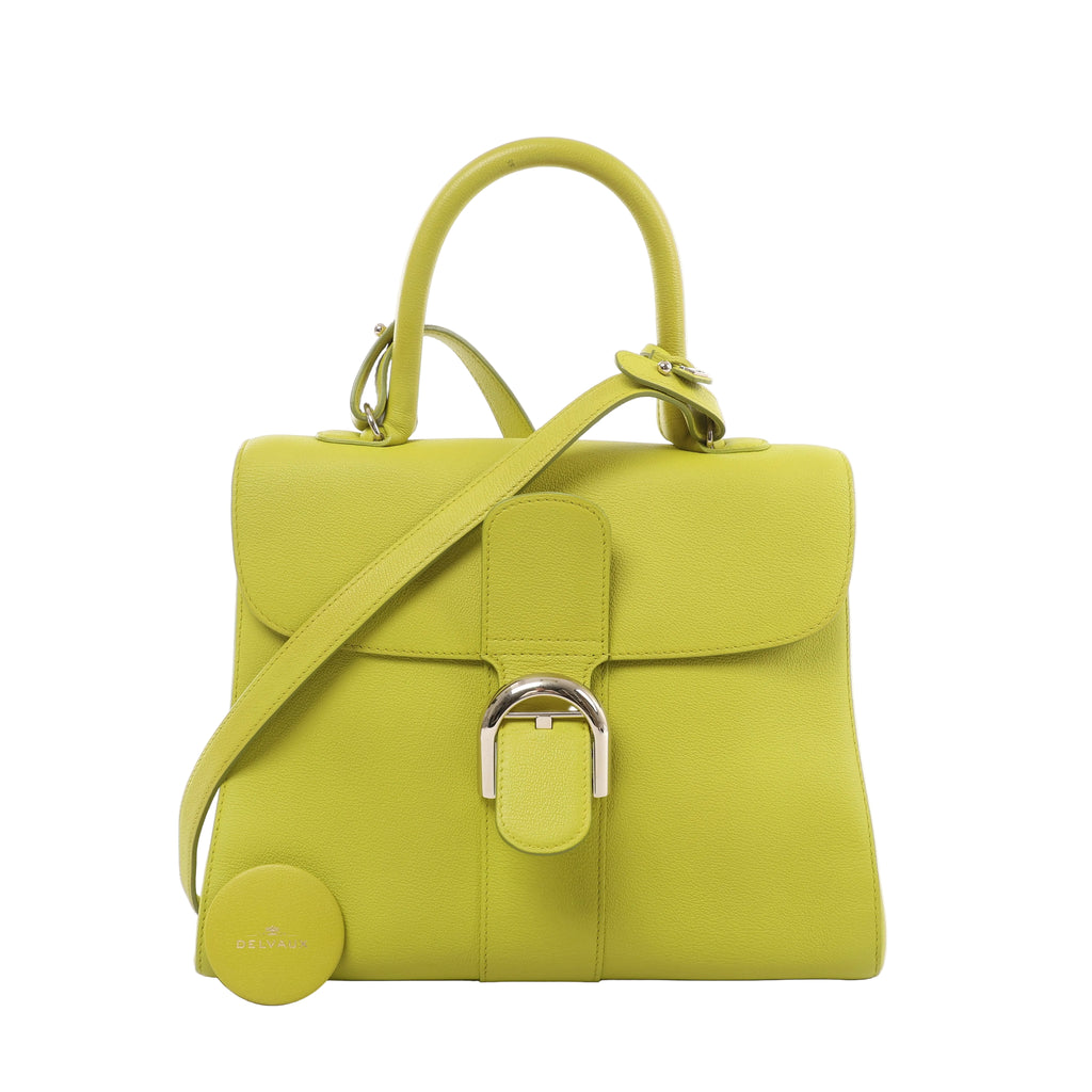 Lime green Delvaux Brillant MM leather handbag with a curved top handle, matching shoulder strap, rounded flap and silver-tone buckle.