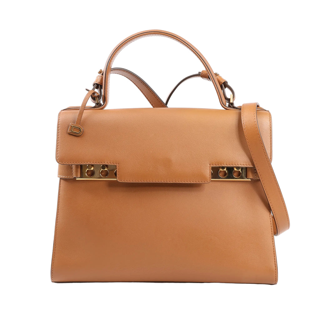 Delvaux Tempête MM handbag in brown leather featuring structured silhouette, gold-tone studded hardware, top handle, and adjustable shoulder strap.