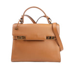 Delvaux Tempête MM handbag in brown leather featuring structured silhouette, gold-tone studded hardware, top handle, and adjustable shoulder strap.