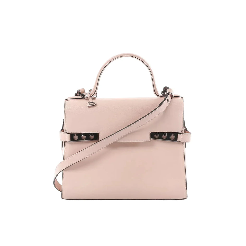 Front view of Delvaux Tempête MM handbag in pale pink leather with top handle, flap front, detachable shoulder strap, and metal side hardware details.