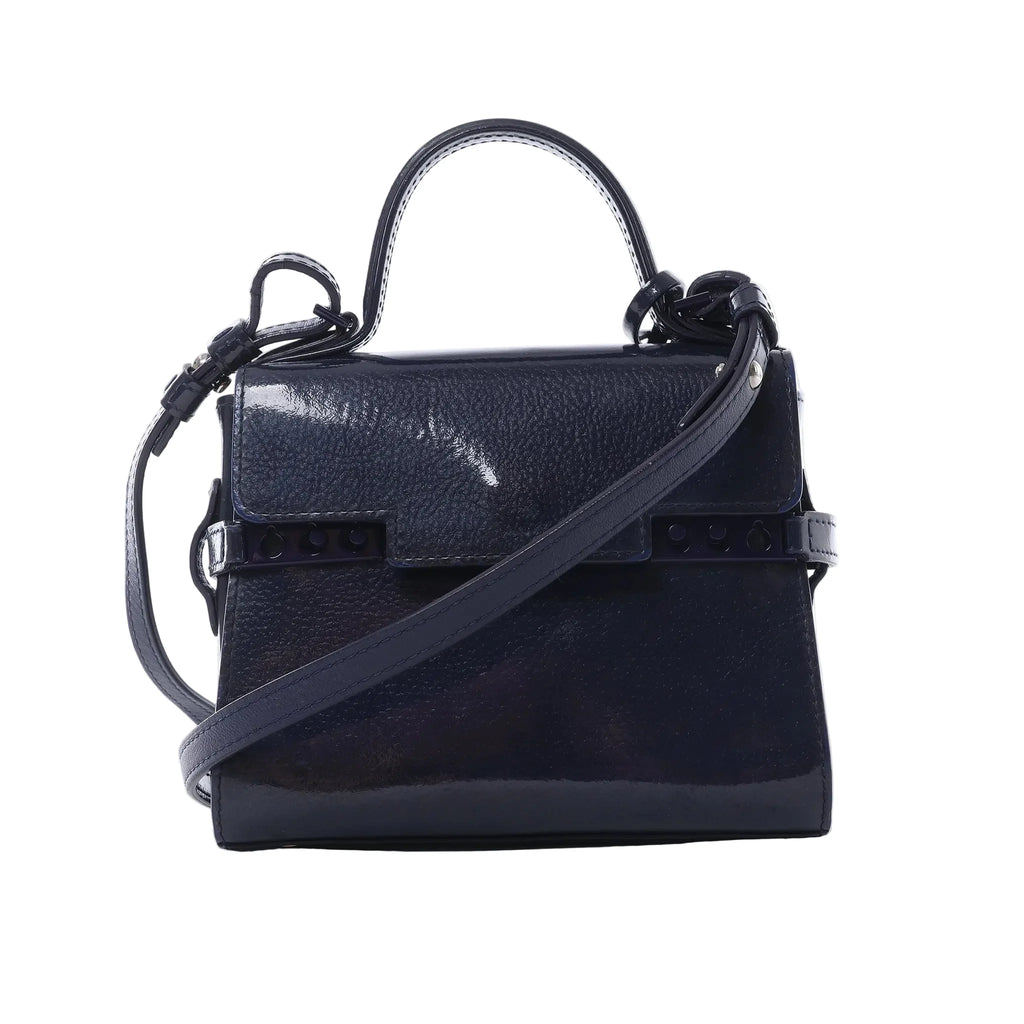 Front view of Delvaux Tempête Mini bag in glossy navy patent leather with top handle, adjustable shoulder strap, flap front, and riveted strap-style detailing.