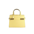 Delvaux Tempête PM yellow leather top-handle bag with gold-tone hardware, studded side accents, and a hanging “D” charm on a white background.
