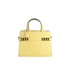 Delvaux Tempête PM yellow leather top-handle bag with gold-tone hardware, studded side accents, and a hanging “D” charm on a white background.