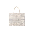 Dior Book Tote Large in gray toile Jouy embroidered canvas with top handles and “CHRISTIAN DIOR PARIS” logo band on the front.