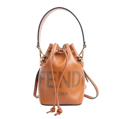 Front-facing image of the Fendi Mon Tresor Mini 2Way Shoulder Bag in brown leather, showcasing drawstring closure, top handle, detachable shoulder strap, and "FENDI ROMA" logo print, with gold-tone hardware, against a white background.