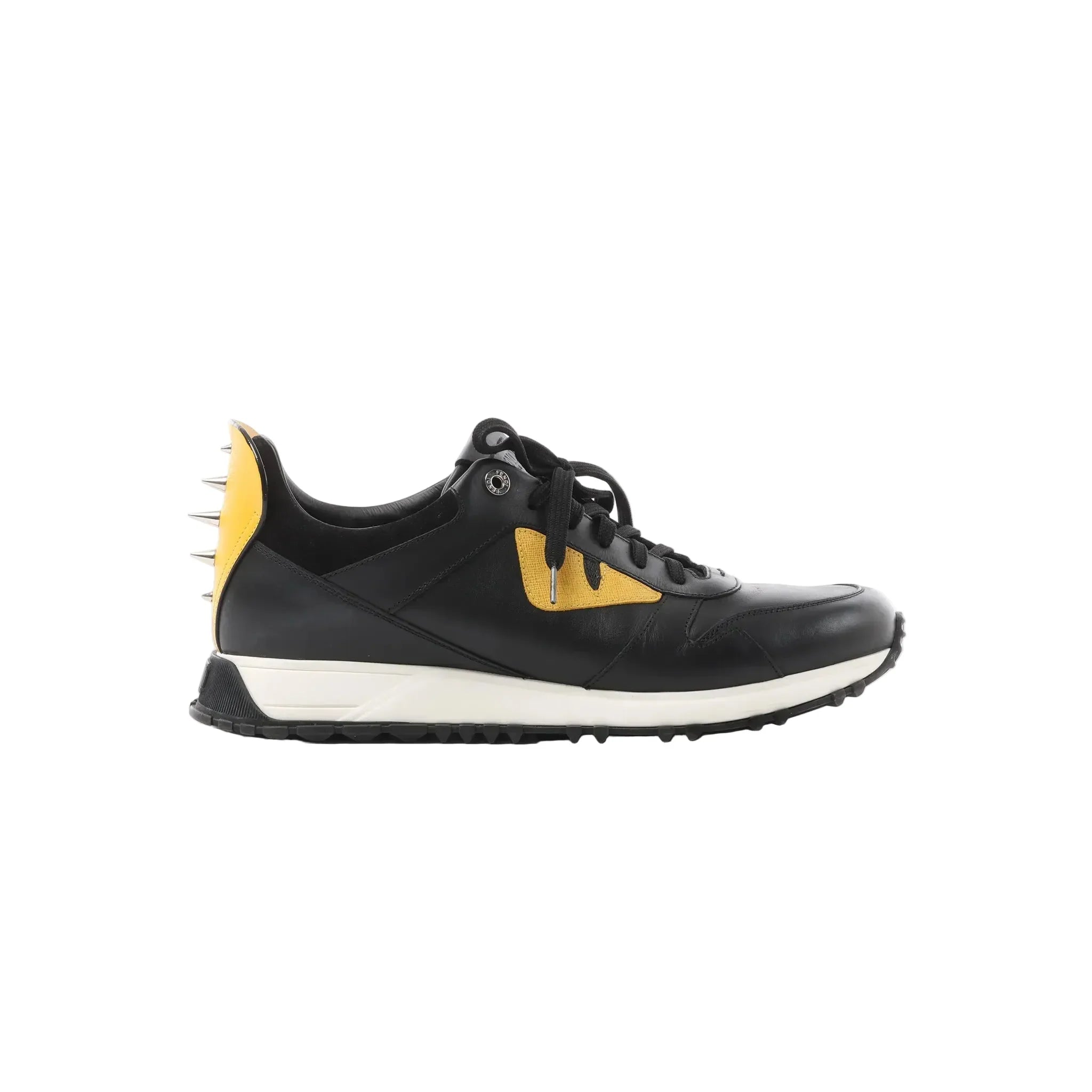 Side view of Fendi black leather sneaker with yellow Bug’s Eye detail, silver spikes at the heel, black laces, and white-and-black rubber sole.
