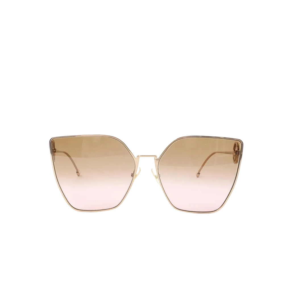 Front view of oversized cat-eye sunglasses with gold-tone metal frame and gradient brown-to-pink lenses on a white background.