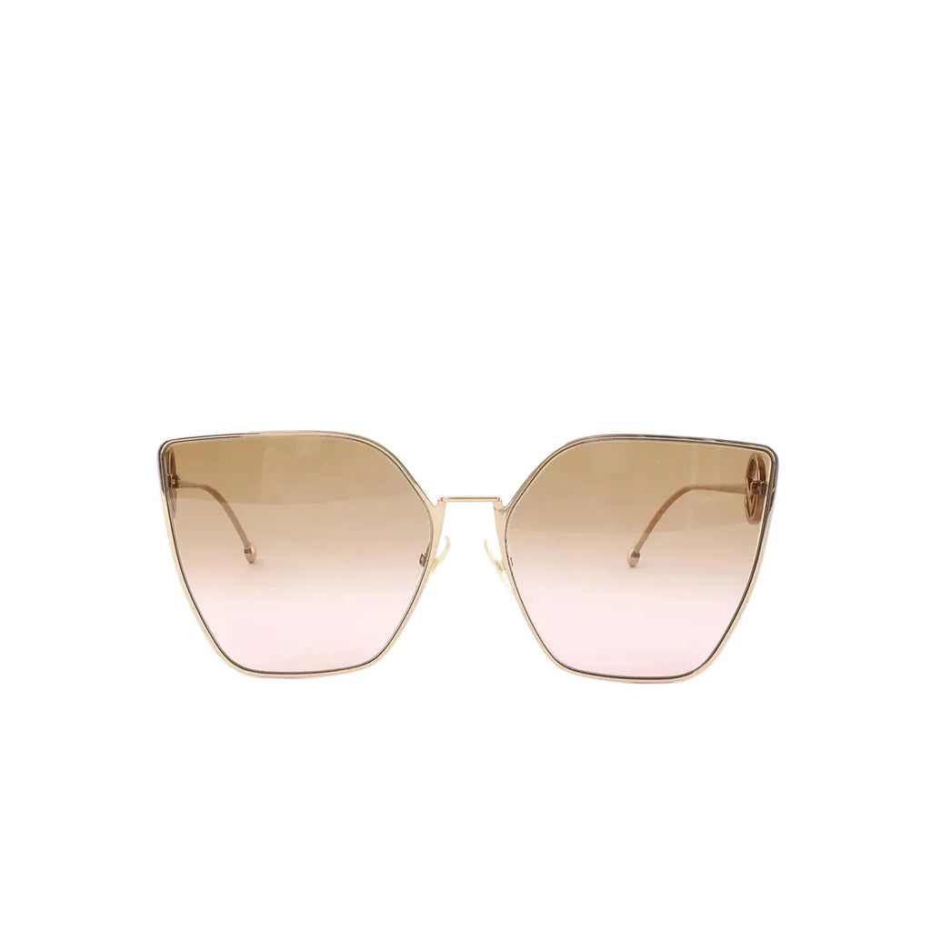 Front view of oversized cat-eye sunglasses with gold-tone metal frame and gradient brown-to-pink lenses on a white background.
