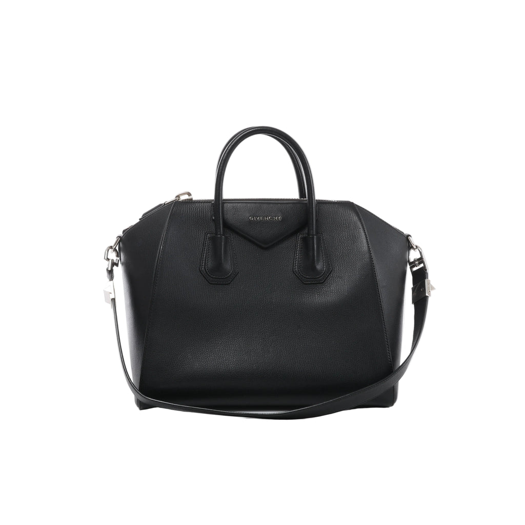 Front view of Givenchy Antigona black grained leather handbag with rounded top handles, a triangular logo patch, shoulder strap and silver-tone hardware.