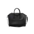 Front view of Givenchy Antigona black grained leather handbag with rounded top handles, a triangular logo patch, shoulder strap and silver-tone hardware.