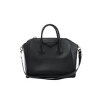 Front view of Givenchy Antigona black grained leather handbag with rounded top handles, a triangular logo patch, shoulder strap and silver-tone hardware.