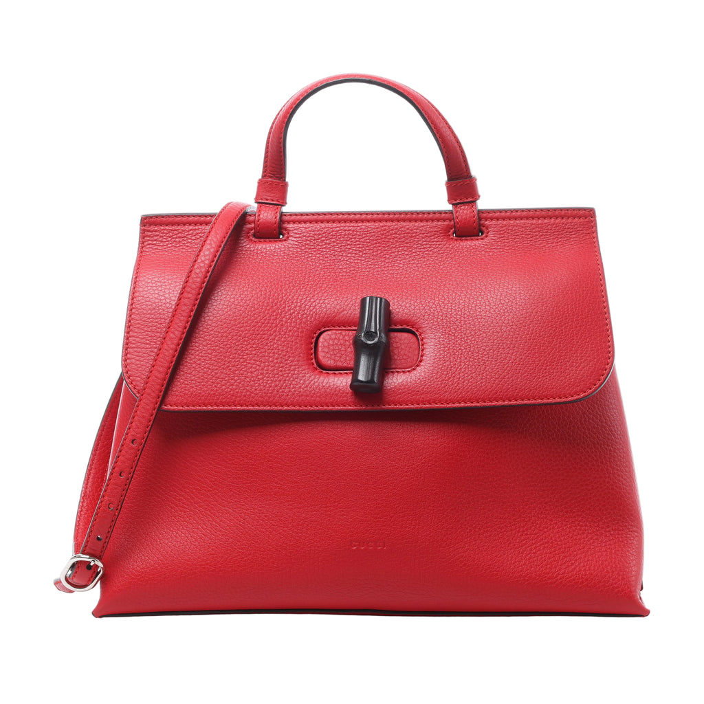 Red Gucci pebbled leather handbag with dual top handles, adjustable shoulder strap and dark bamboo-style front closure.