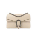 Gucci Dionysus small beige leather crossbody bag with silver-tone chain strap and crystal-embellished horseshoe closure on white background.