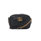Black Gucci GG Marmont mini crossbody bag in chevron quilted leather with gold-tone Double G logo and chain strap on white background.