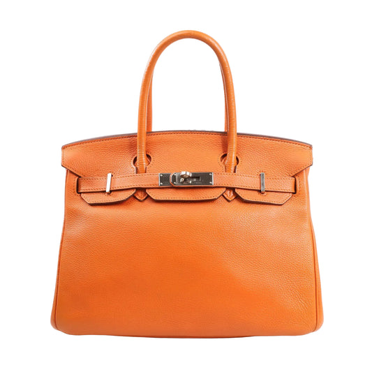 Hermès Birkin 30 handbag in bright orange Togo leather featuring dual rolled handles, palladium-tone hardware, signature flap with lock and clochette, and structured silhouette.