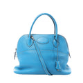 Hermès Bolide 31 bright blue pebbled leather handbag with rounded top handles, shoulder strap, clochette, zip closure, and silver-tone hardware on white background.