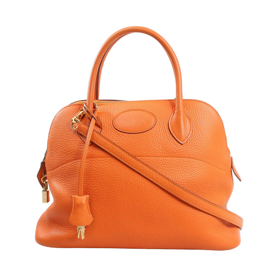 Hermès Bolide 31 handbag in orange Taurillon Clemence leather (2004), featuring rounded top handles, detachable shoulder strap, gold-tone hardware, zip closure, and a matching clochette with keys.