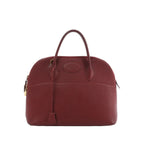 Hermès Bolide 35 handbag in red pebbled leather with top handles, zip-around closure, hanging clochette, and gold-tone hardware on a white background.