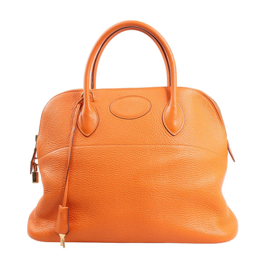 Front view of the Hermès Bolide 35 handbag (□G:2003) in bright orange Taurillon Clemence leather, featuring a rounded structured shape, dual rolled handles, gold-tone hardware, and clochette with keys.
