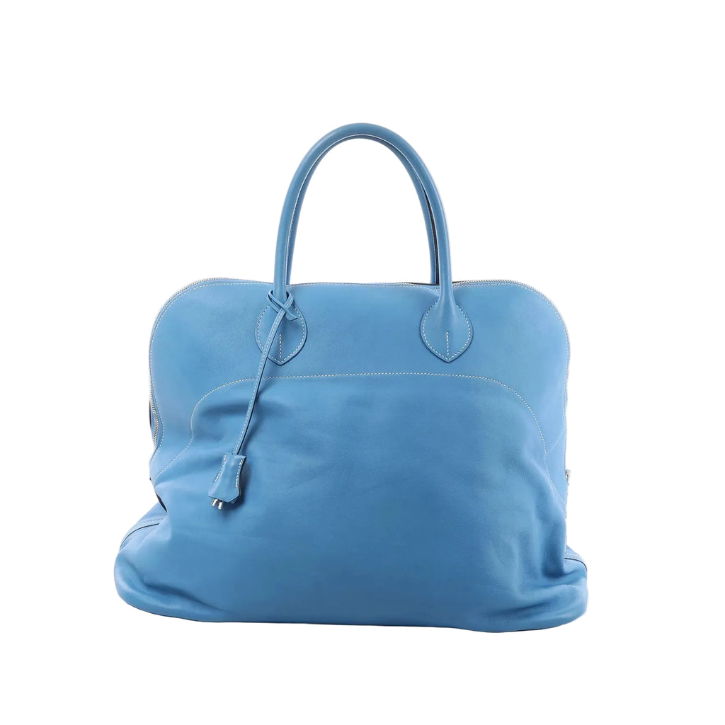 Hermès Bolide Relax 45 handbag in azure blue leather with top handles, zip-around closure, and hanging clochette on a white background.