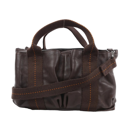 Front view of the Hermès Caravan Horizontal PM 2Way Handbag in Chocolat brown Veau Derma leather, showcasing soft gathered leather texture, dark brown fabric handles and strap with orange stitching, and silver-tone hardware, displayed against a white background.