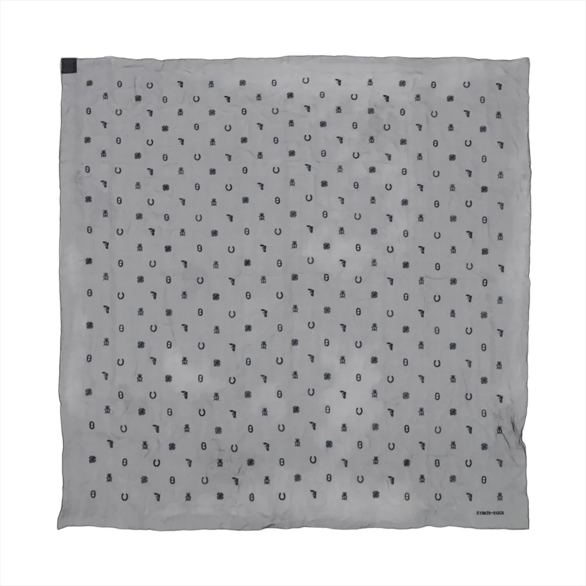 Hermès Carré 100 black silk scarf with repeating small charm motifs in dark tones across the surface and Hermès Paris signature in the corner.