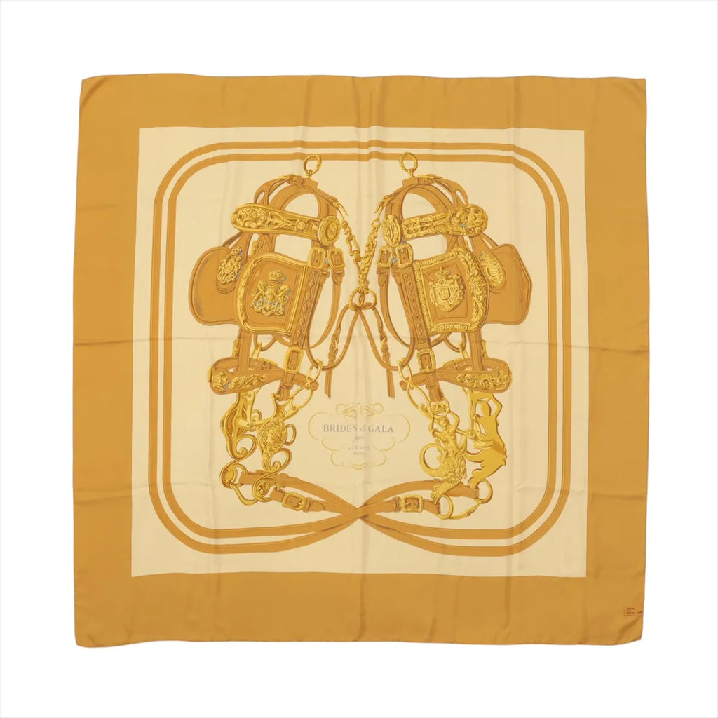 Hermès Carré 140 “Brides de Gala” silk scarf in brown tones with large central bridle and tack illustration on a cream ground and brown border.