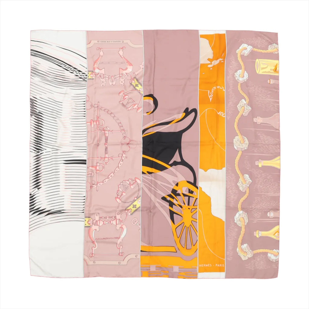 Hermès Carré 140 silk scarf in pink and beige with panelled design featuring equestrian hardware motifs and orange carriage wheel graphic, laid flat on white background.