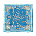 Hermès Carré 70 blue silk scarf with crown motif, ornate tan scrollwork pattern, and light blue border, laid flat