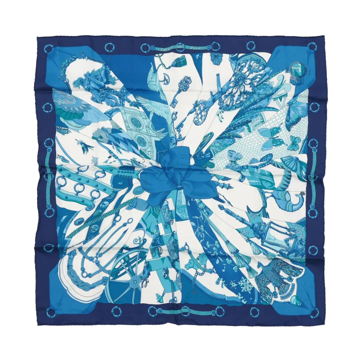 Hermès Carré 70 “Soleil de Soie” silk scarf in blue with navy border, blue sunburst-style panels, and central bow motif.