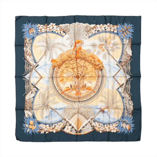 Hermès Carré 90 "Aloha" silk scarf in navy blue and beige featuring tropical birds perched in a large tree, surrounded by palm trees, ocean waves, coconuts, and floral patterns in a Hawaiian island-inspired design.