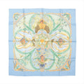 Hermès Carré 90 "Amazonia" silk handkerchief in blue, featuring intricate depictions of jungle foliage, birds, butterflies, a jaguar, and indigenous figures framed by golden botanical motifs, set against a soft sky-blue border for a rich tropical aesthetic.