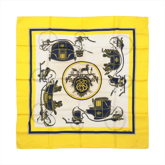 Hermès Carré 90 "Attelage en Arbalète" silk handkerchief in yellow, showcasing a symmetrical navy and gold carriage motif with a central medallion and bold yellow border.