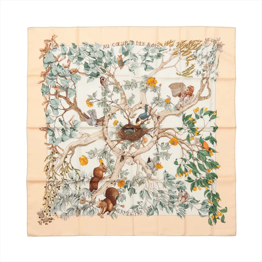 Hermès Carré 90 "Au Cœur des Bois" silk scarf in beige featuring a detailed illustration of a forest tree filled with birds, squirrels, leaves, and flowers, evoking the heart of the woods in soft, earthy tones.