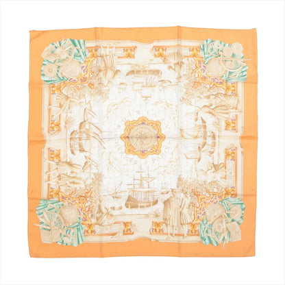 Hermès Carré 90 "Azulejos" silk scarf in orange, showcasing an ornate compass at the center surrounded by ships, explorers, and classical motifs in beige tones, with corner accents of globes and instruments in turquoise and coral.