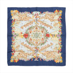 Hermès Carré 90 “Au Pays de Cocagne” silk scarf with navy border, central architectural landscape design, and multicolor floral and fruit border.