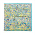 Flat view of a square Hermès Carré 90 silk scarf with a turquoise border and yellow field filled with blue floral, bird and botanical motifs.